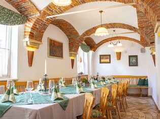 Cozy room with set table and historical brick walls. | © Gasthof Lend-Platzl
