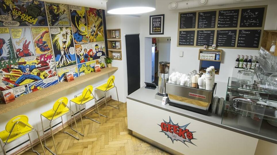 Caffè accogliente con decorazione a fumetti e sgabelli. | © Geeks Cafe