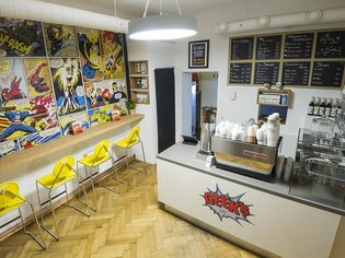 Caffè accogliente con decorazione a fumetti e sgabelli. | © Geeks Cafe
