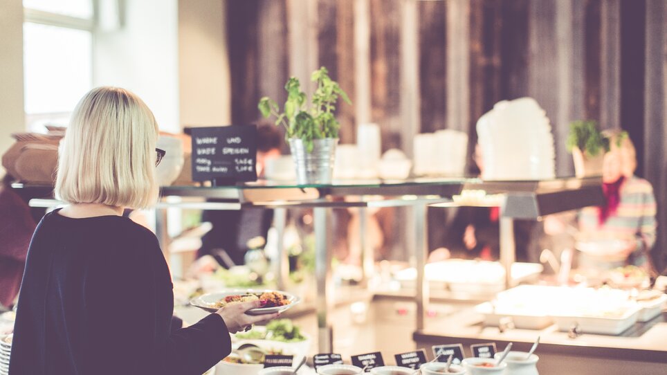 Eine Person holt sich Essen an einem Buffet. | © Lupi Spuma 