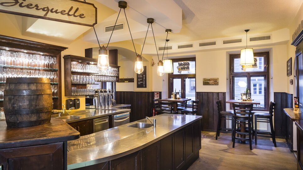 The interior of a bar featuring a wooden counter and glasses. | © Glöckl Bräu