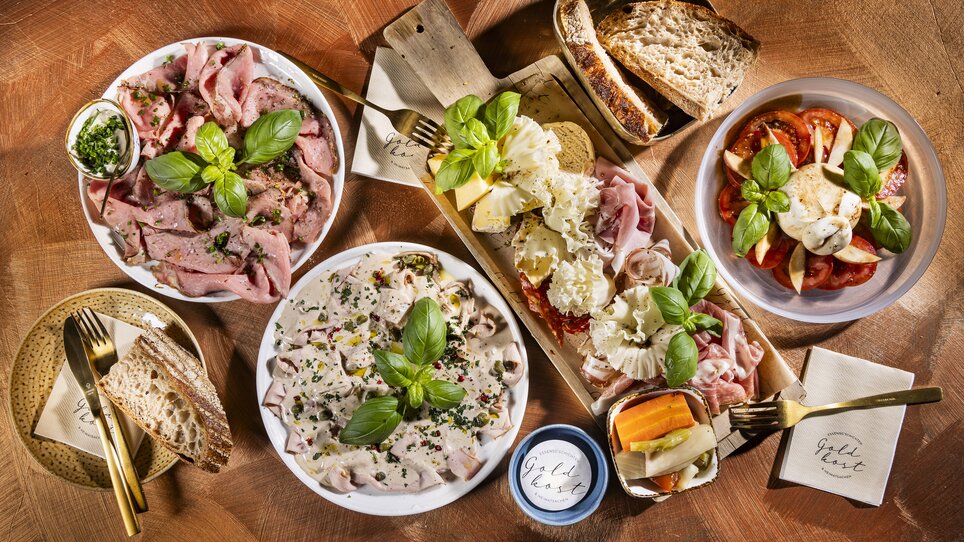 Varietà di piatti e snack su un tavolo, circondati da basilico fresco. | © Werner Krug