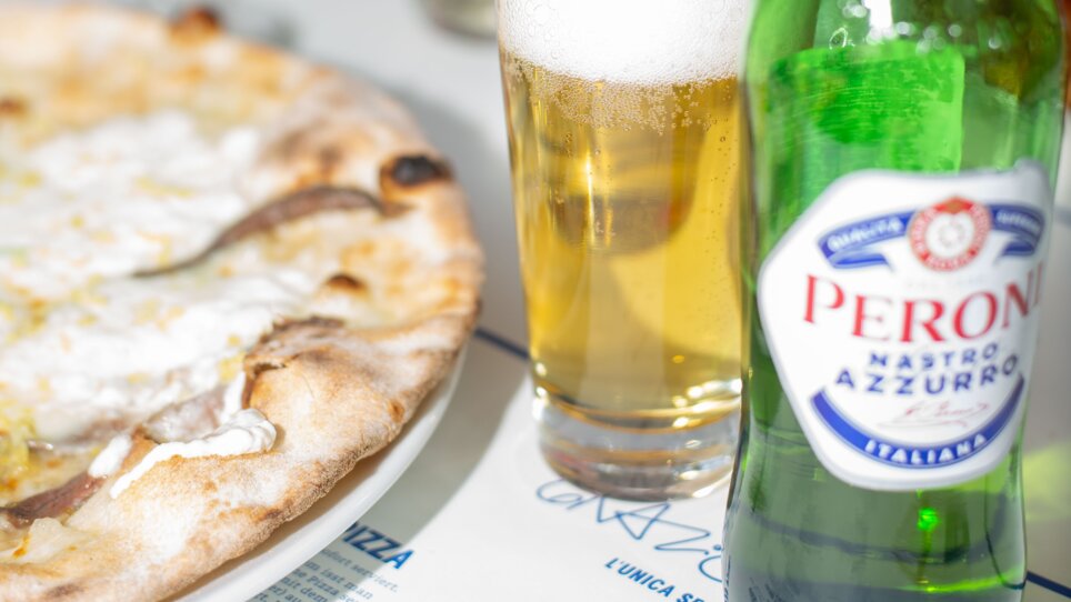Beer and Stracciatella pizza at the Grazie Roma restaurant in Graz, with glasses in the background. | © Florian Weitzer Hotels & Restaurants