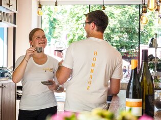 Due membri dello staff in un caffè ridono e gustano bevande a Graz. | © Hommage