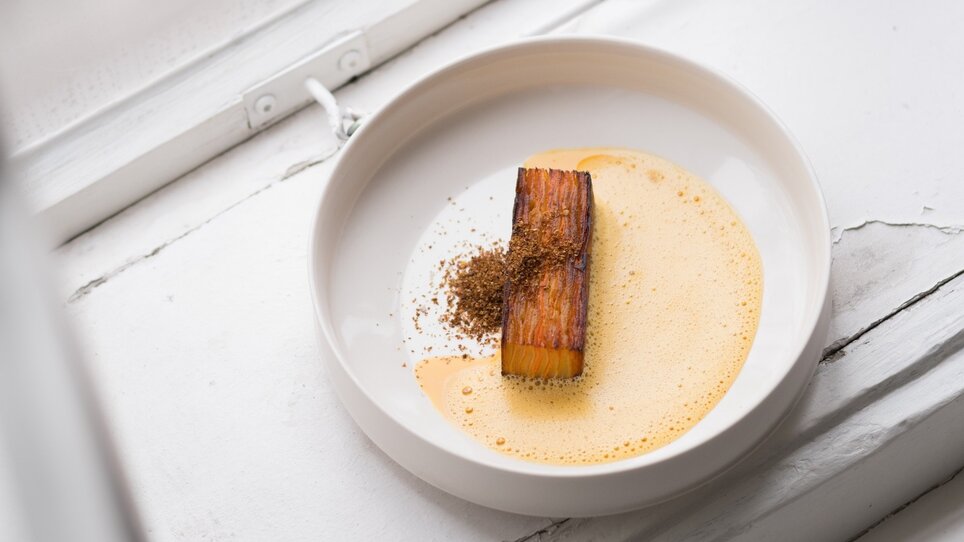 Un piatto creativo su un piatto bianco con salsa gialla e spezie. | © Kabuff