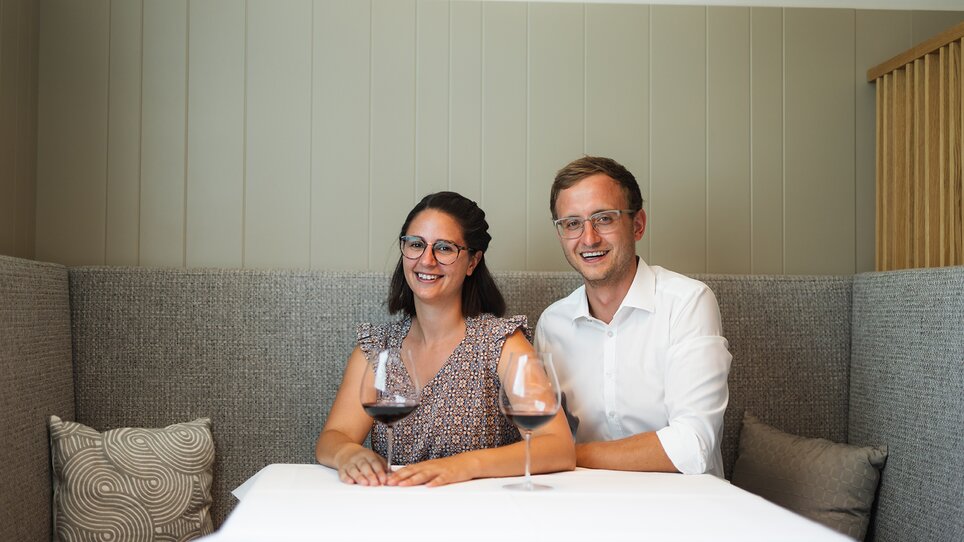 Paar sitzt mit Weingläsern an einem Tisch im Gasthaus. | © Studio Lou