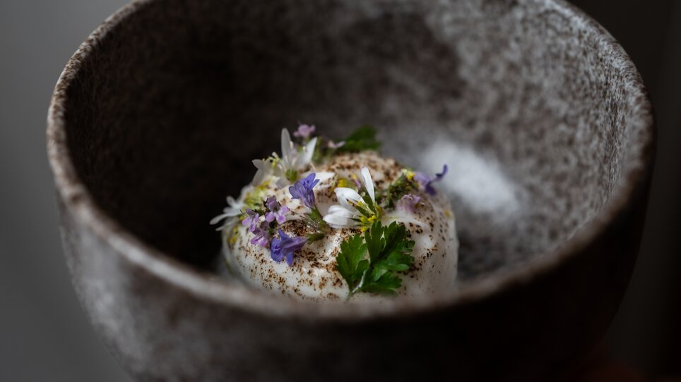 An artistically presented dish with flowers and herbs. | © Studio-Lou - Lukas Elsneg