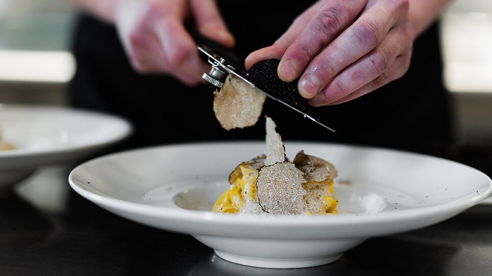 Uno chef guarnisce un piatto con tartufo. | © Studio Lou