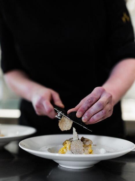 Uno chef guarnisce un piatto con tartufo. | © Studio Lou