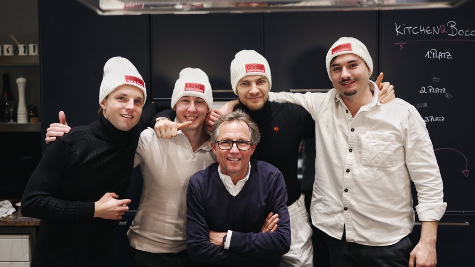 The Kitchen12 team: A group of five people, four of them are wearing white hats, are standing in the Kitchen12 kitchen. | © Makinson Media