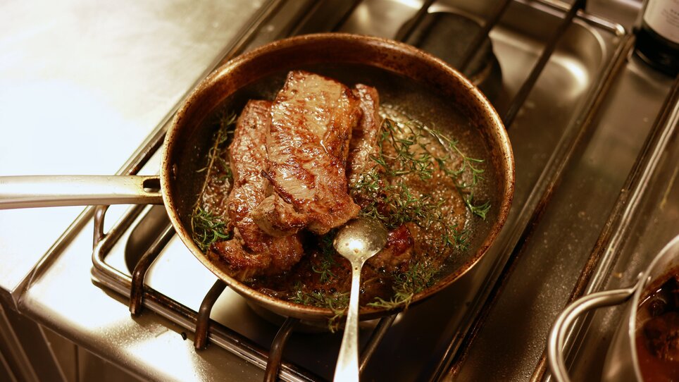 Cooking tender steaks in a pan with thyme. | © Makinson Media