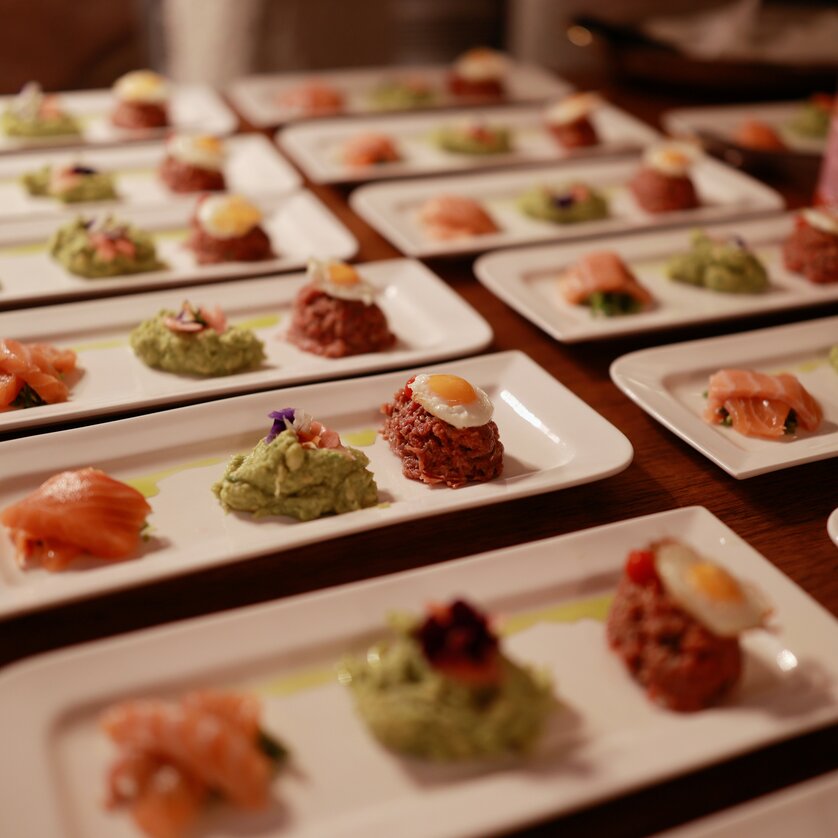 Elegant plates with high-quality appetizers, including salmon and various spreads. | © Makinson Media