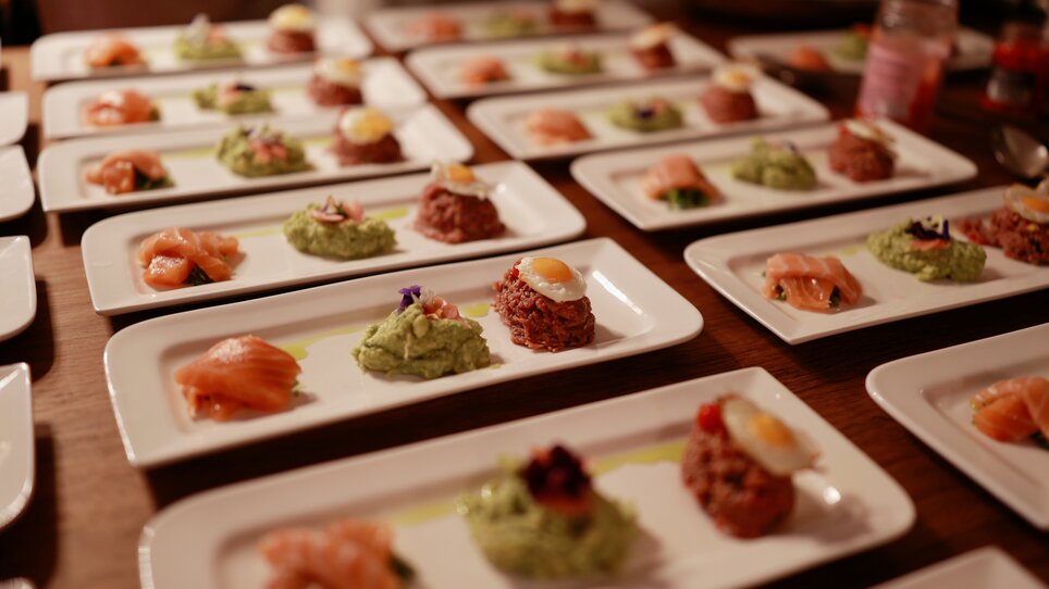 Elegant plates with high-quality appetizers, including salmon and various spreads. | © Makinson Media