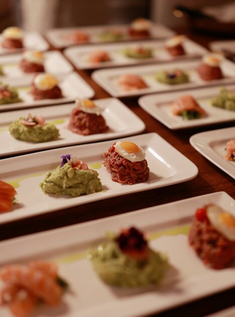 Elegant plates with high-quality appetizers, including salmon and various spreads. | © Makinson Media