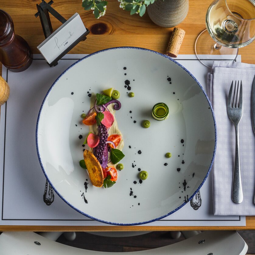 An artfully arranged plate with fresh fish and vegetables.