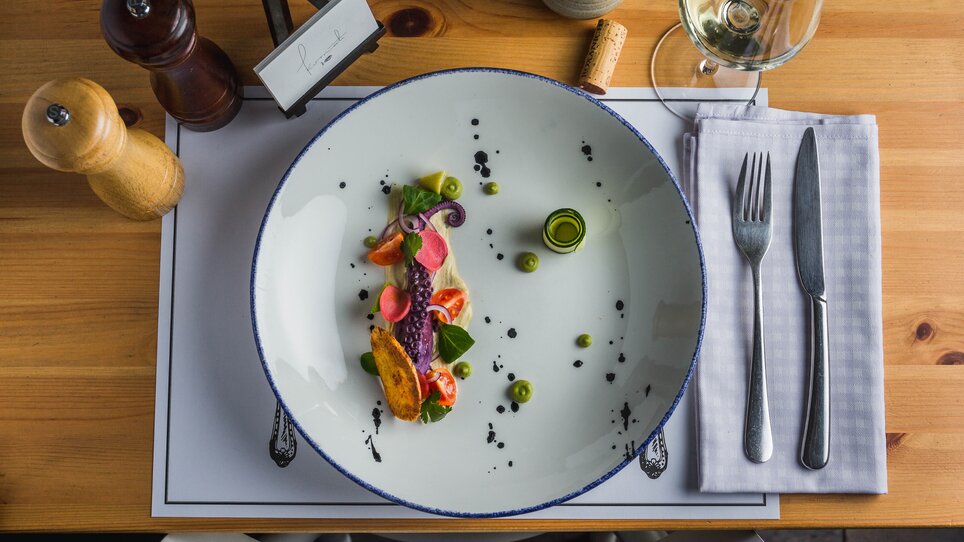 An artfully arranged plate with fresh fish and vegetables.