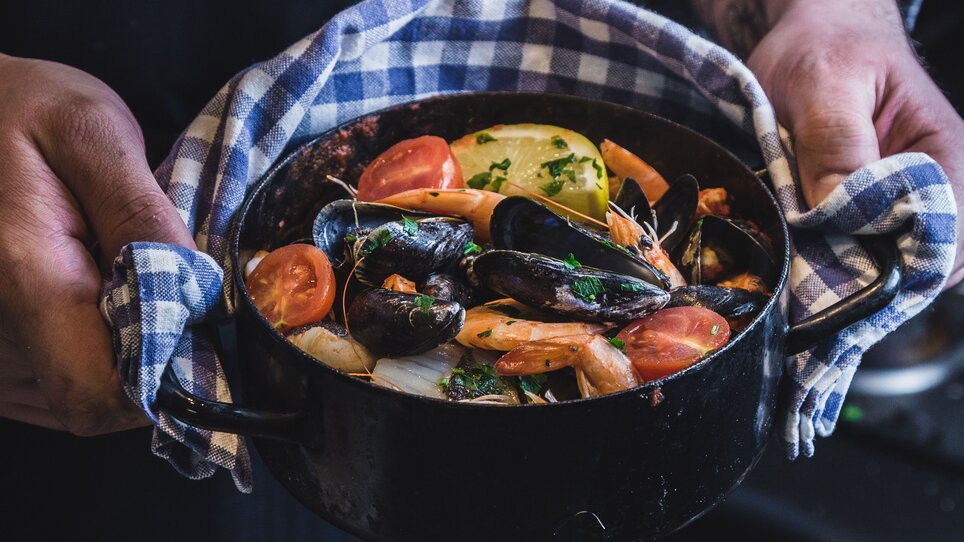 A chef holding a pot of seafood dish.