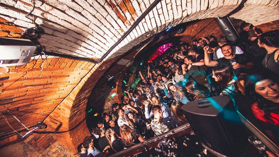 Crowded club with people dancing and an arched ceiling.