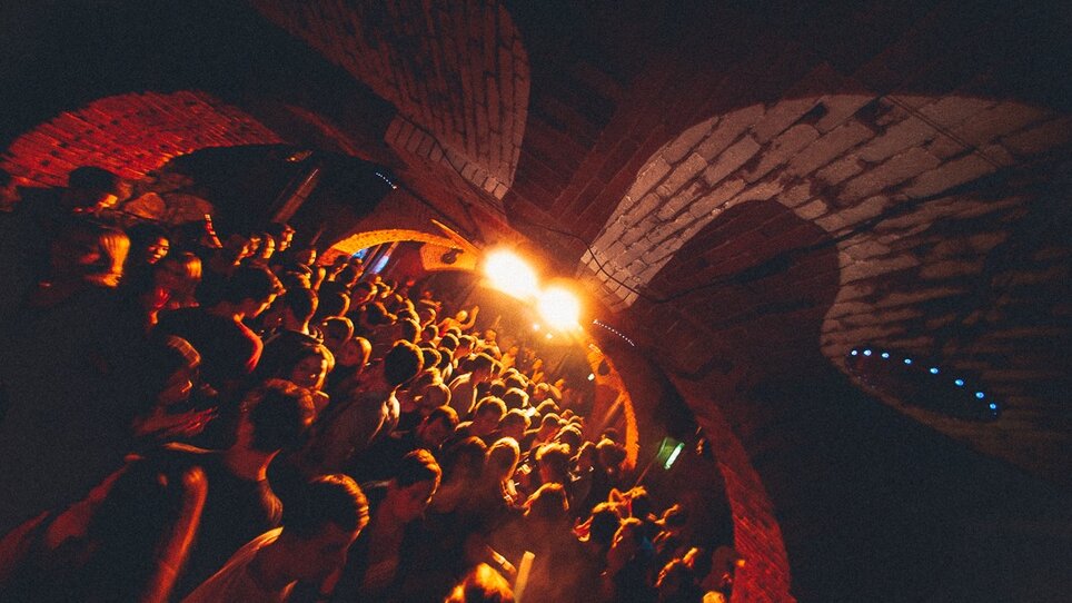 Crowded club in Kottulinsky with dancing people and atmospheric lighting.