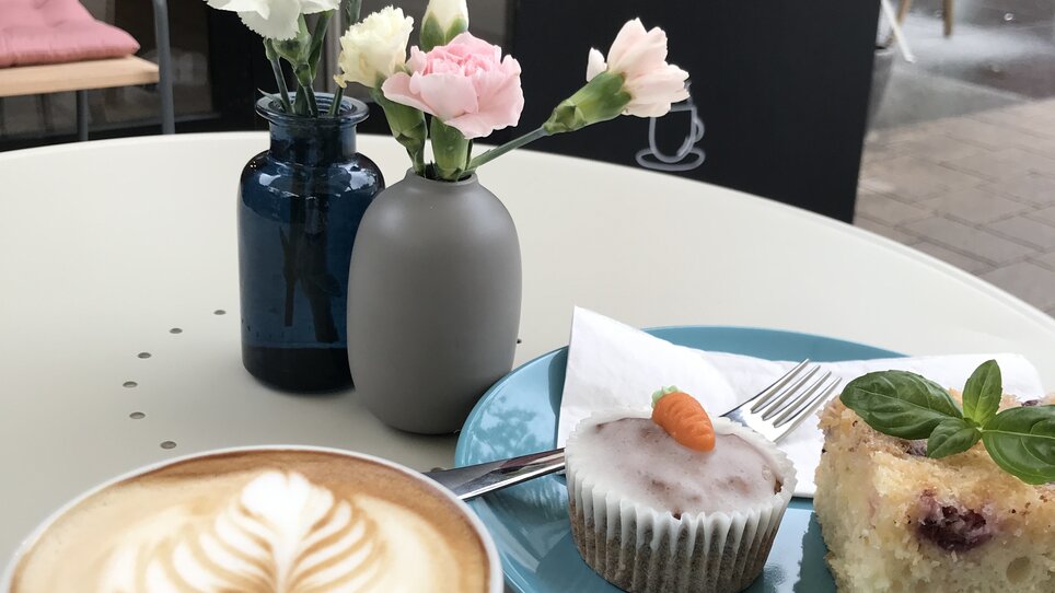 Coffee, cake, and fresh flowers at a café.