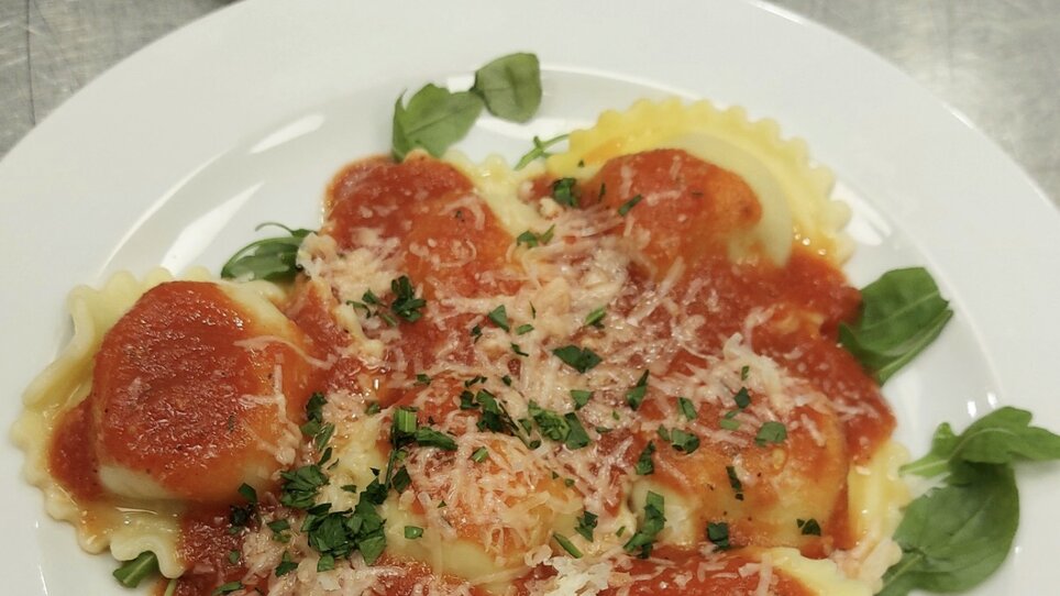Ravioli with tomato sauce and parmesan, garnished with herbs. | © Foto Vision