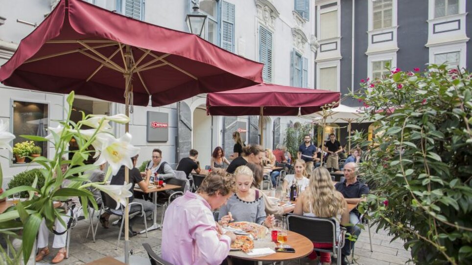 Lebhafte Außenterrasse von L'Osteria Graz mit Gästen. | © L`Osteria 