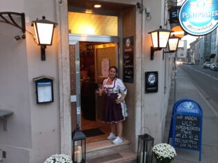 A woman stands in front of Märzenstüberl in Graz with drinks. | © Märzenstüberl