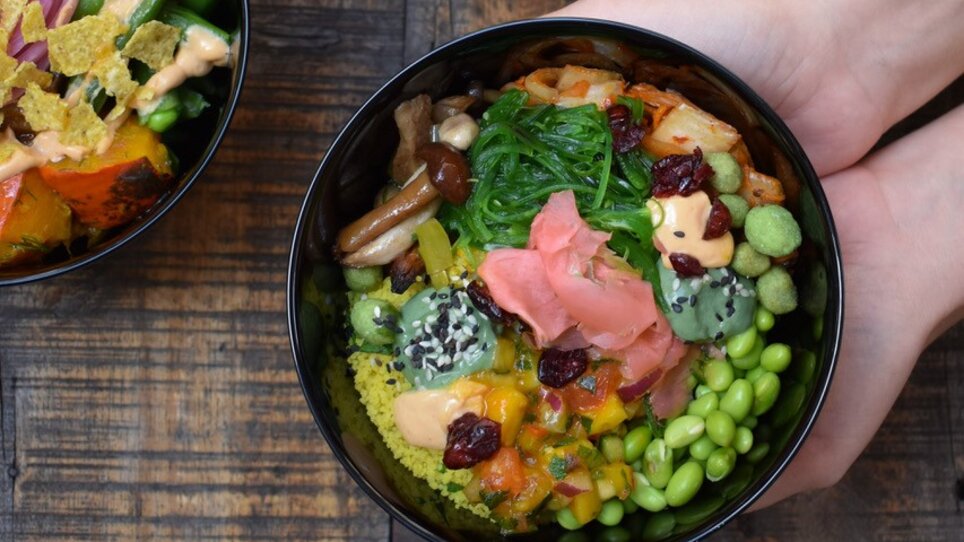 Ciotole colorate con piatti salutari su un tavolo di legno, inclusi verdure e riso. | © Mangolds