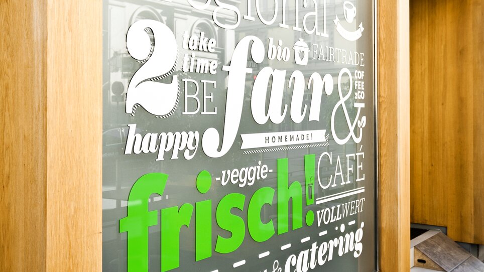 Insegna sulla finestra che evidenzia opzioni regionali e vegane da Mangolds a Graz. | © Mangolds (4a)