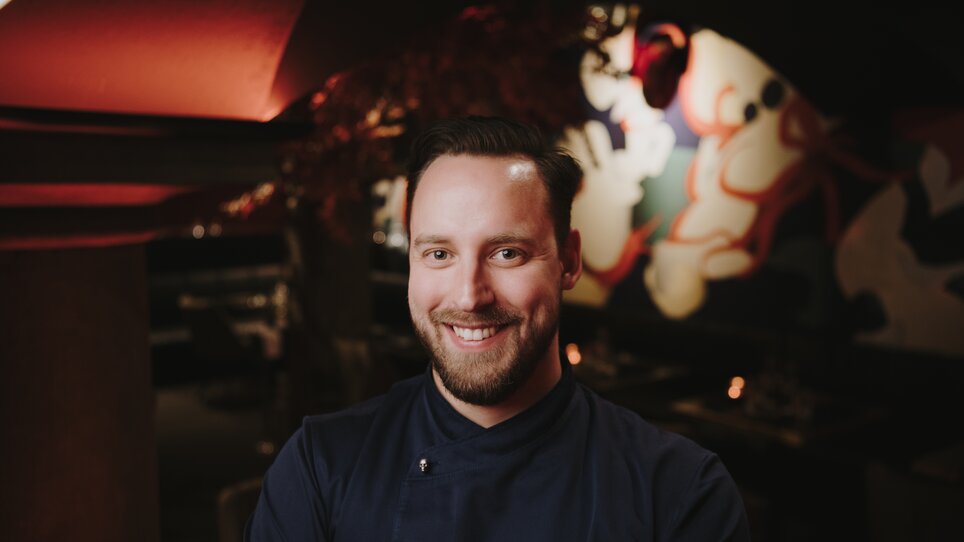 Un cuoco sorridente in un ristorante con decorazioni moderne.