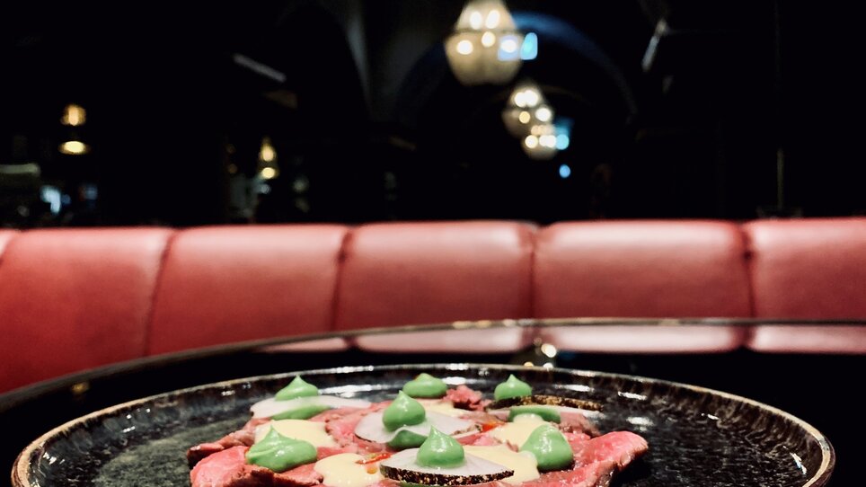 Carpaccio di manzo su un piatto in luce soffusa.