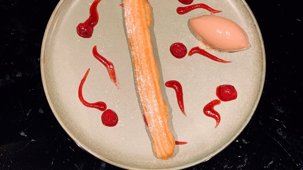 Dessert con churro e sorbetto servito su un piatto.