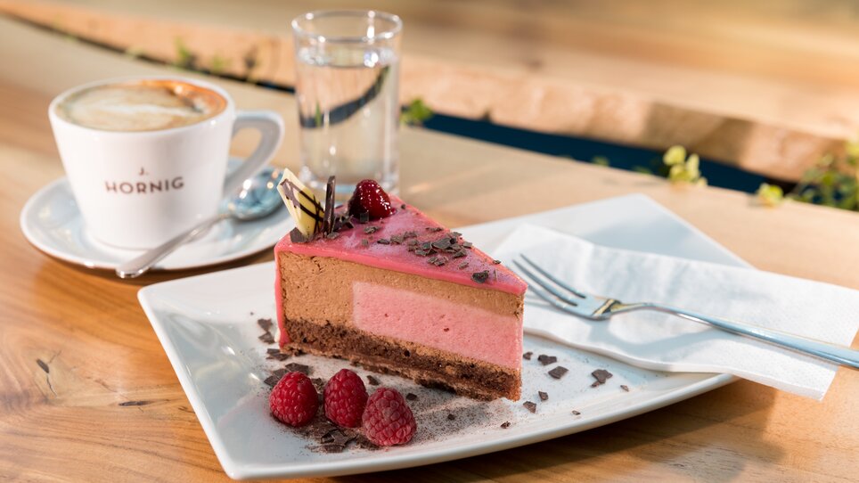 A slice of cake with raspberries and an espresso on a table. | © Harry Schiffer