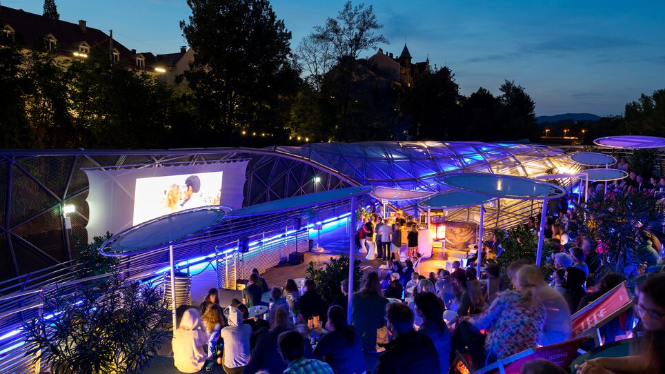 Night view of the Murinsel Café with guests and light effects. | © Harry Schiffer