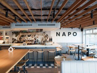 Moderne Restaurantansicht mit Bar und Napo-Schriftzug. | © fiedlerphoto