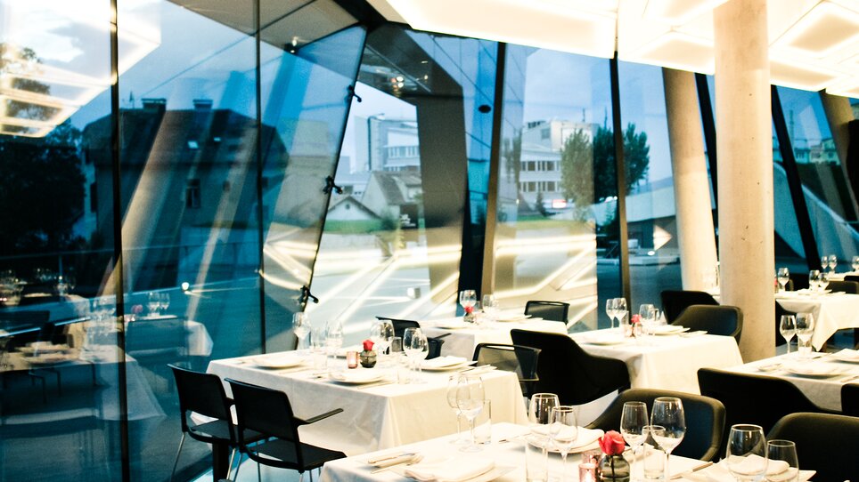Elegant restaurant in Graz with modern furniture and panoramic view. | © nullneun
