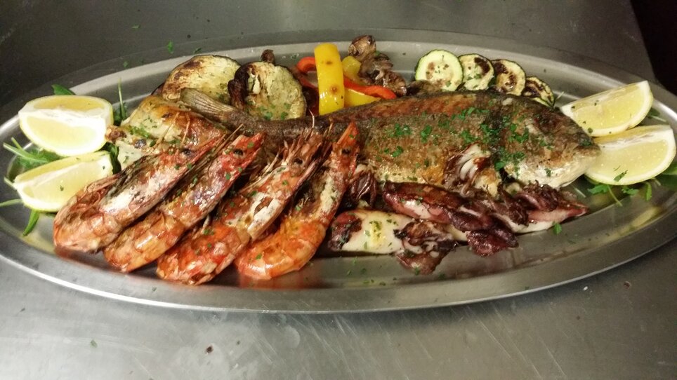 Ein Platte mit Fisch und Meeresfrüchten, dekoriert mit Zitrone und Kräutern. | © Osteria dei Sensi