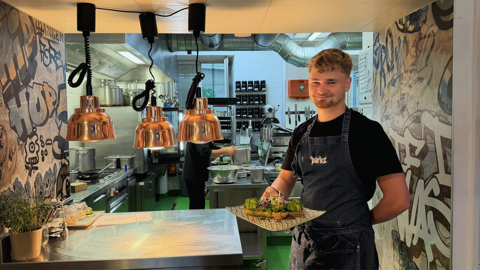 Giovane cuoco presenta un piatto al caffè PARKS a Graz. | © Graz Tourismus