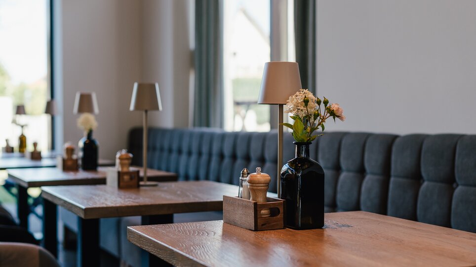 Inviting interior view of a restaurant with wooden tables and flowers. | © Pastaria