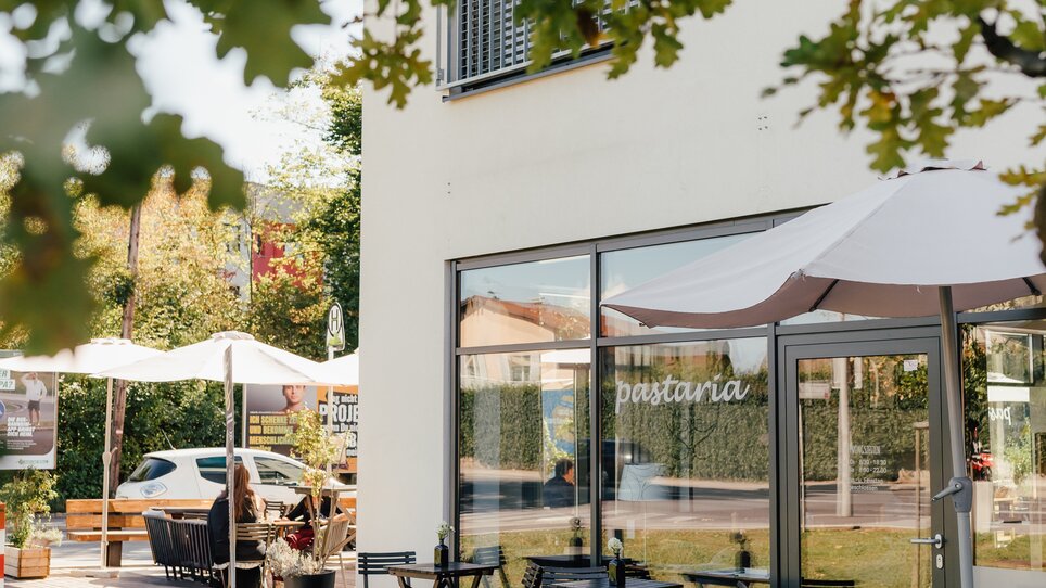 Exterior view of Pastaria with tables and umbrellas. | © Pastaria