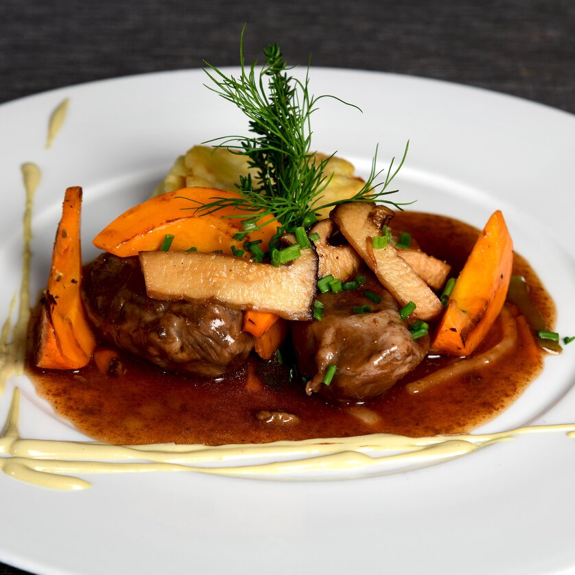 Un piatto ben presentato con carne, verdure e salsa. | © Rainer Juriatti