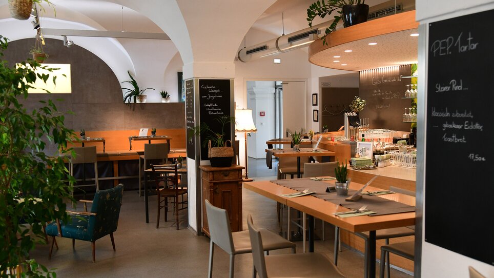 Cozy restaurant interior with plants and menus. | © Rainer Juriatti