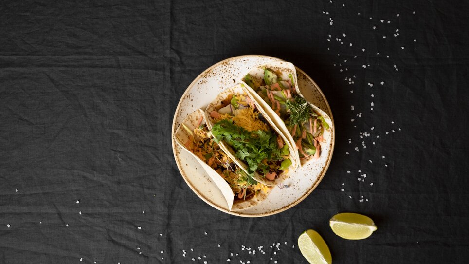 Three delicious tacos on a plate, garnished with fresh ingredients and lime wedges. | © Jauk Katharina