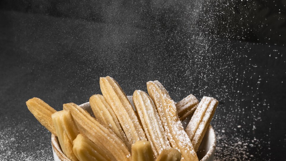 A bowl of churros dusted with powdered sugar. | © Jauk Katharina