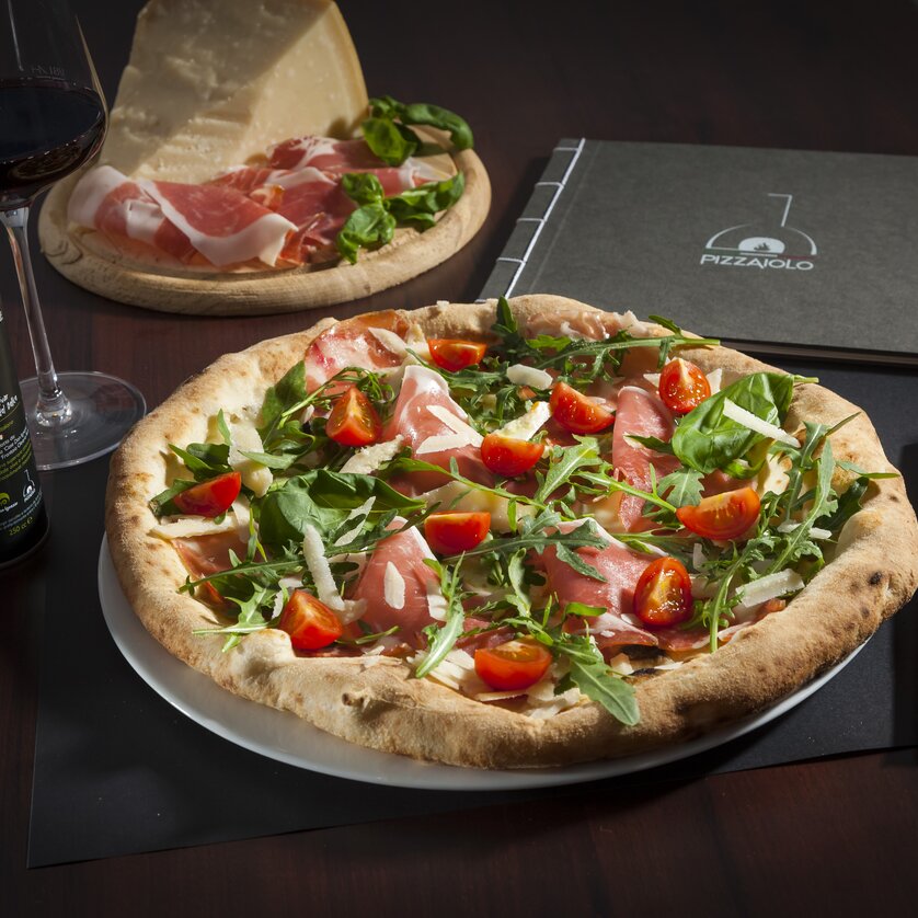 Pizzaiolo - Pizzeria napoletana Graz I Mangiare e bere a Graz Pizza deliziosa con prosciutto, rucola e pomodori a Graz.