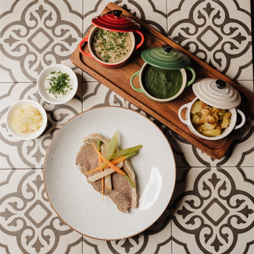 Ein Teller mit Fleisch und Gemüse, dazu verschiedene Beilagen im Topf. | © Restaurant Florian