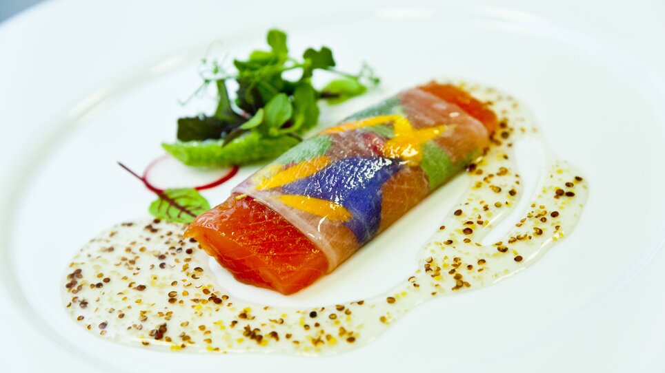 A creatively plated dish with salmon and colorful vegetables.