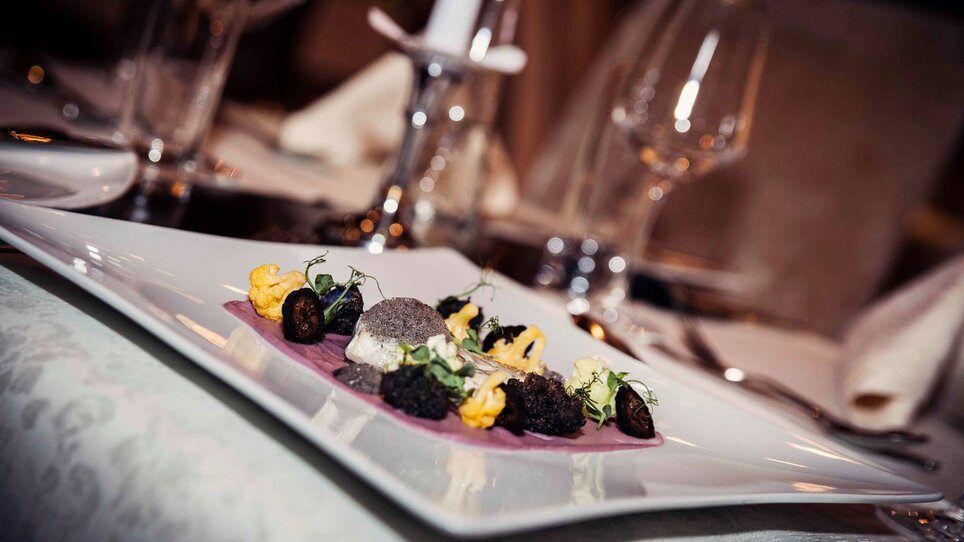 An elegant dish on a white plate with various ingredients.