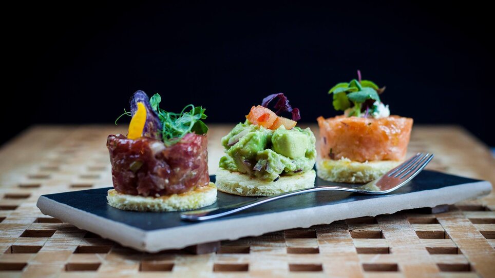 Three small dishes on a plate, attractively arranged.
