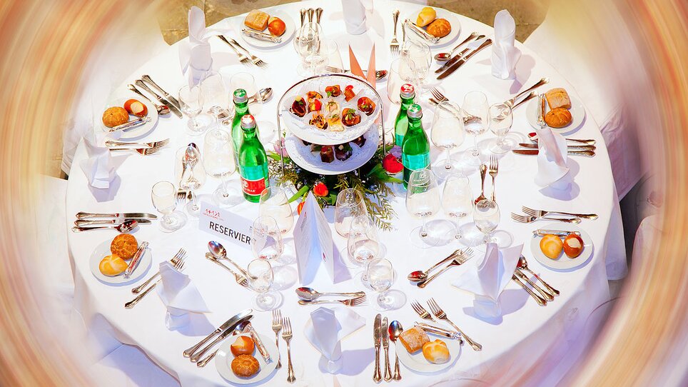 Elegant set dining table with drinks, food, and decorations.